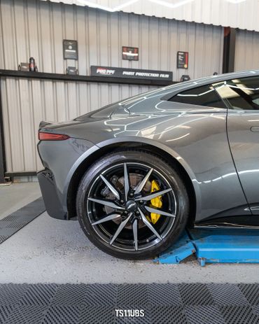Close-up of a sleek sports car's rear wheel with yellow brake calipers.
