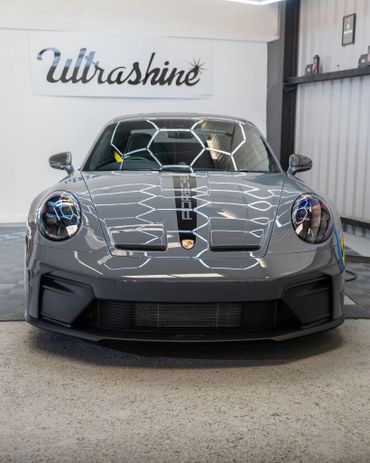 Front view of a sleek gray Porsche sports car inside a showroom.