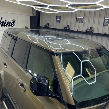 A modern SUV under hexagonal ceiling lights inside a garage.