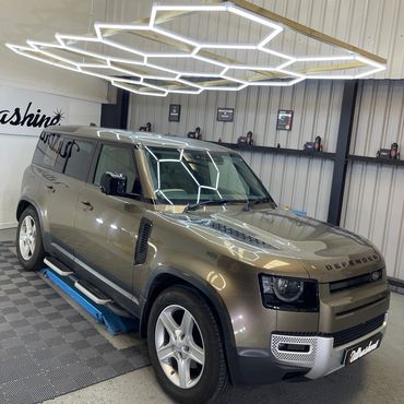 Shiny Land Rover Defender in a modern, well-lit garage.