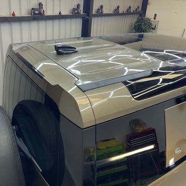 Rear view of a shiny Land Rover vehicle inside a well-lit garage.