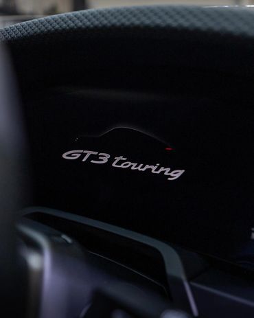 Illuminated GT3 Touring logo with car silhouette on dashboard.