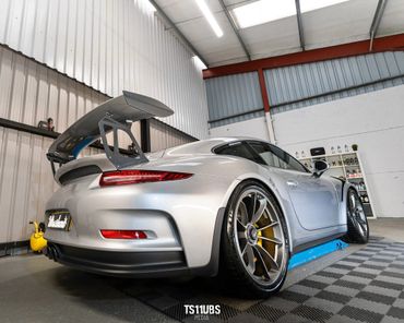 Silver sports car with a large rear wing in a garage.