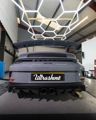 Rear view of a sleek Porsche GT3 with a prominent spoiler inside a garage.