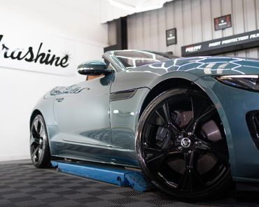 Sleek Jaguar convertible on a blue lift in a showroom.