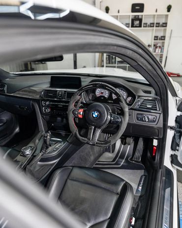 BMW M4 interior with carbon fiber steering wheel and sporty design.