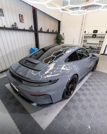 Sleek gray sports car parked indoors with modern lighting reflections.