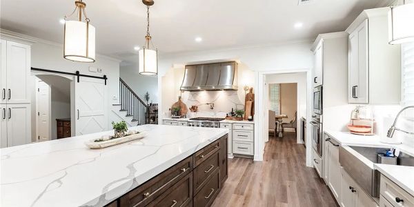 Modern kitchen with white cabinets and marble island.