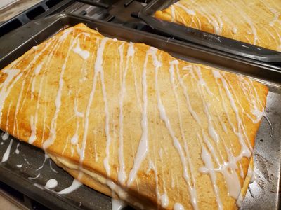 Freshly baked cinnamon rolls with icing on baking trays.