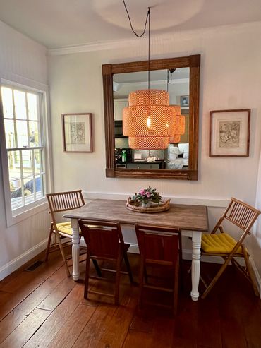 Cozy dining area with wooden table, mixed chairs, and a woven pendant light.