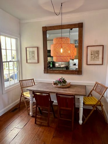 Cozy dining area with wooden table, mixed chairs, and a woven pendant light.