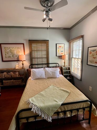 Cozy bedroom with a metal bed frame, warm lighting, and wooden blinds.