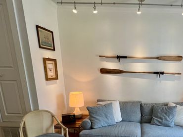 Cozy living room with blue sofa, wooden chairs, and nautical decor.