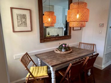 Cozy dining area with wooden table, rattan chairs, and warm pendant lights.