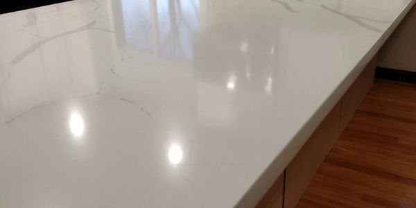 Glossy white marble countertop with subtle veining and wooden floor.