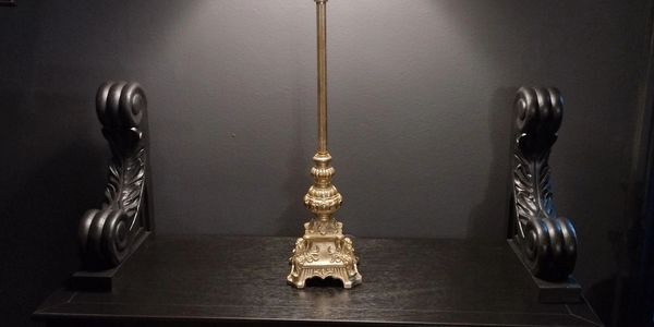Ornate golden lamp on a dark wooden surface with carved armrests.