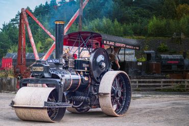 Vintage steamroller with workers in a rustic outdoor setting.