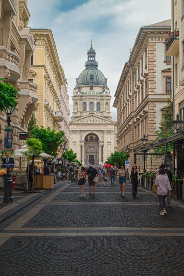 Busy pedestrian street leading to a grand historic cathedral with a large dome.