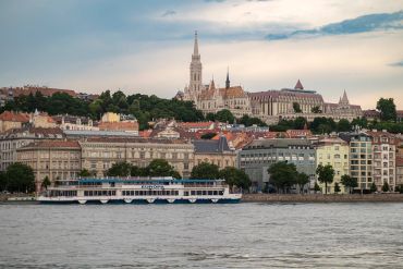 River cruise boat with historic buildings and a church in the background.