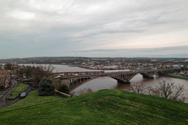 A wide view of a bridge over a river with a cloudy sky.