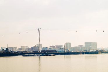 Cable cars crossing a river with a city skyline in the background.
