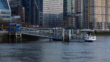 Canary Wharf ferry pier with modern buildings in the background.