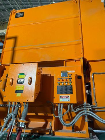 Orange industrial control panels with wiring and labels mounted on a large machine.