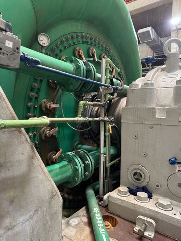 Industrial machinery with interconnected green pipes and gauges.