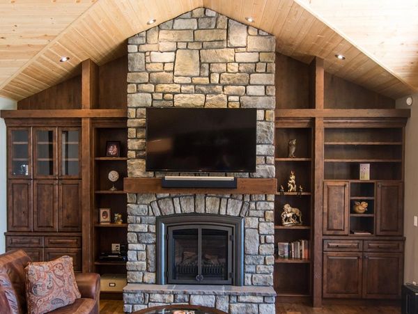 Stone fireplace and built-in wood cabinets and shelving.