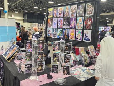 Art booth display with framed prints, metal bookmarks, and curated artwork at a convention