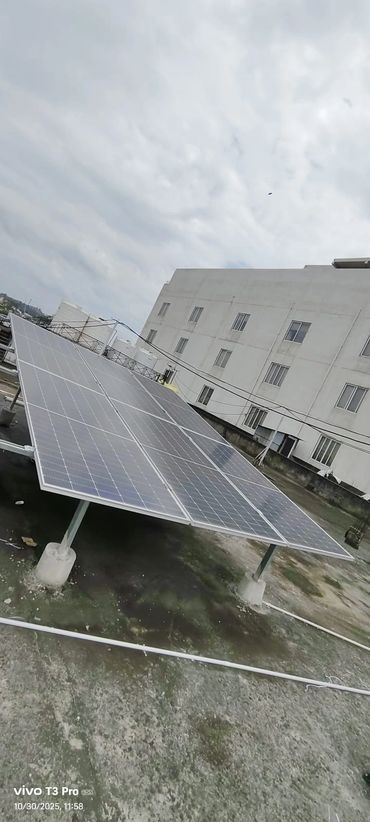 Solar panels installed on a rooftop under a cloudy sky.