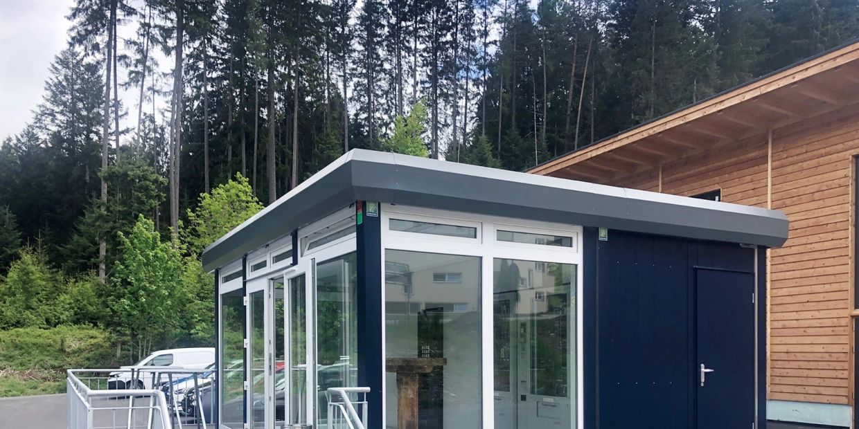 Modern portable modular building with glass walls and metal ramp outside.