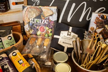 A cozy kitchen shelf with cookbooks, spices, utensils, and dish towels.