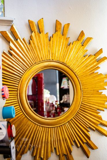 Decorative golden sunburst mirror with a round reflective center.