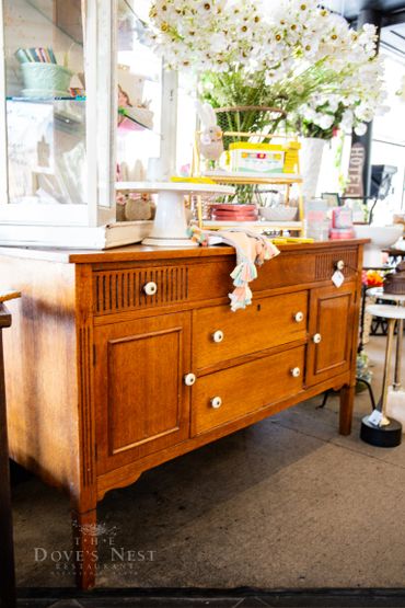 Vintage wooden sideboard with white knobs displayed in a bright shop setting.