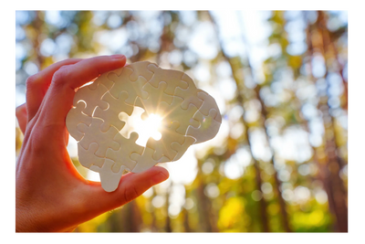 Puzzle of a brain with a hand holding it, one piece of the puzzle is missing