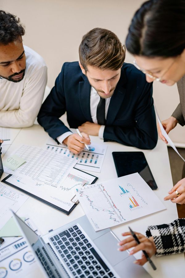 A group of business people sit reviewing business performance documents.