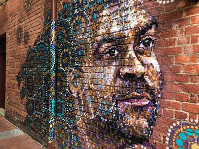 An portrait of an indigenous man on a brick wall