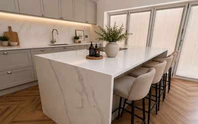 Modern neutral fitted kitchen with island and herringbone flooring – Osprey Interiors