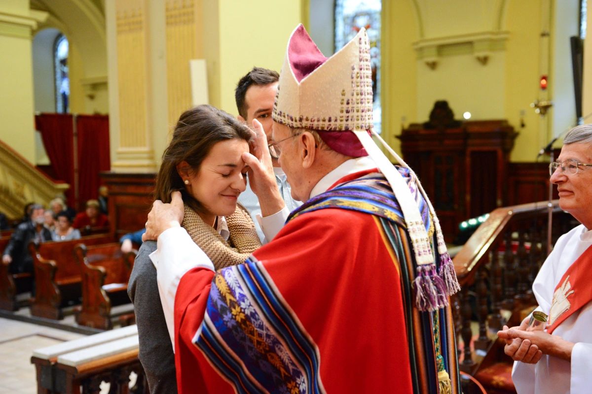 A bishop blesses a young woman during a church ceremony.