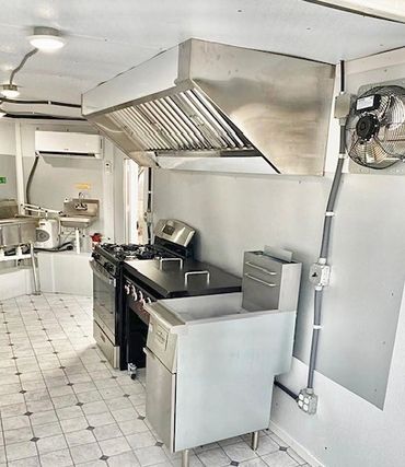 Clean commercial kitchen with stainless steel appliances and ventilation hood.