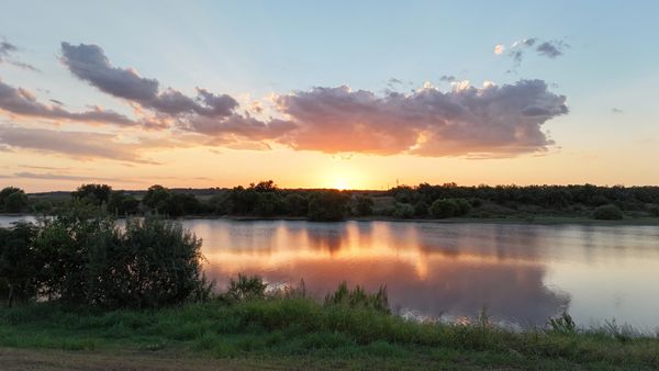 Sunset over a lake with reflections and clouds.