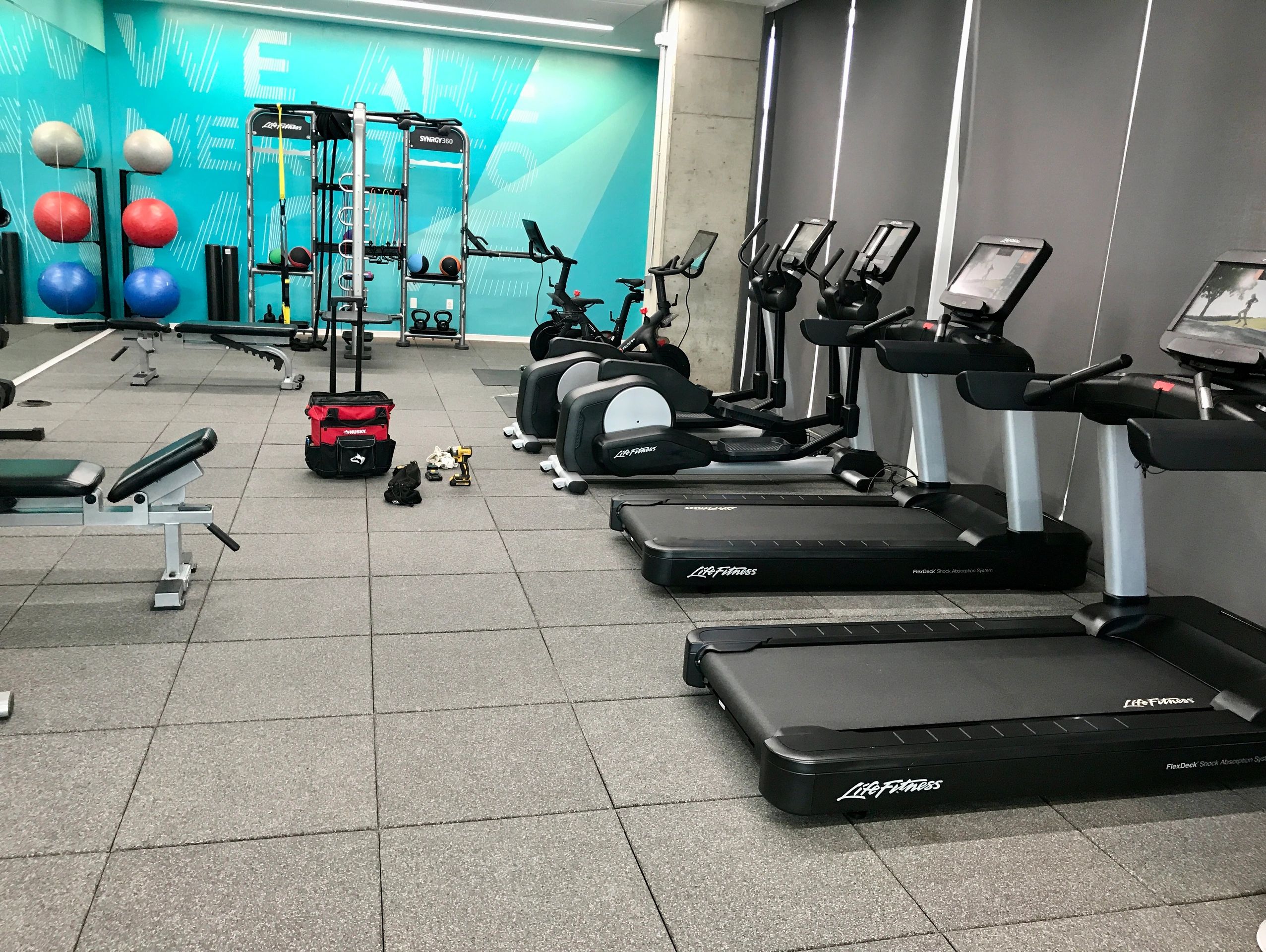 Modern gym with treadmills, ellipticals, and exercise balls.