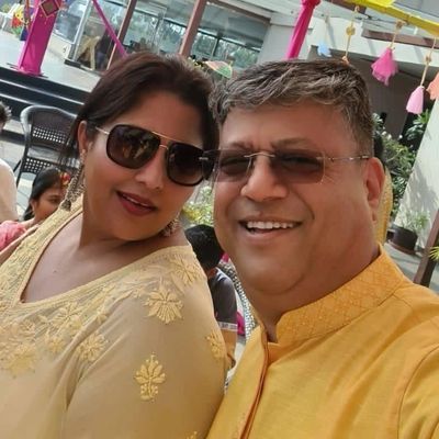 A smiling couple wearing matching yellow outfits and sunglasses.