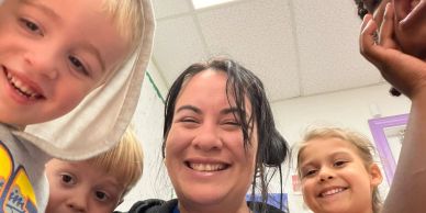 Smiling woman and children posing for a selfie indoors.
