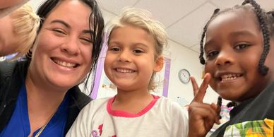 Three people smiling and posing for a selfie indoors.