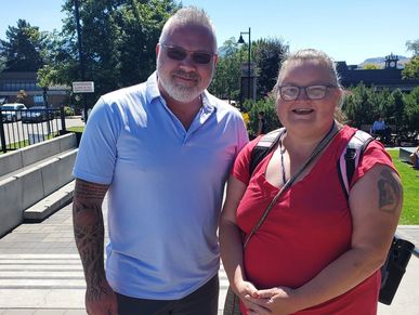 Two smiling people outdoors in casual clothes.