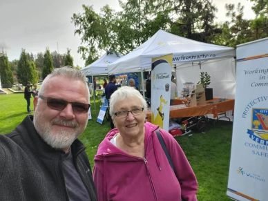Two people smiling at an outdoor fair with tents.