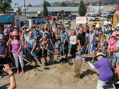 Group ground-breaking event with shovels and sand.