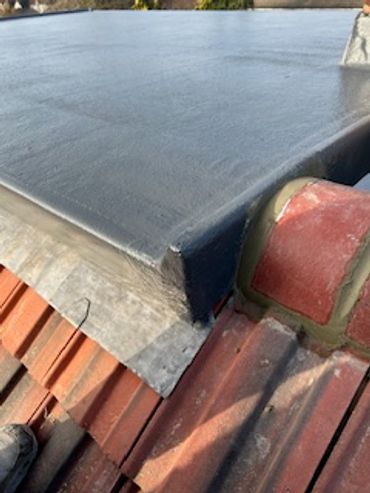 Newly applied black waterproof roofing layer on flat rooftop corner.